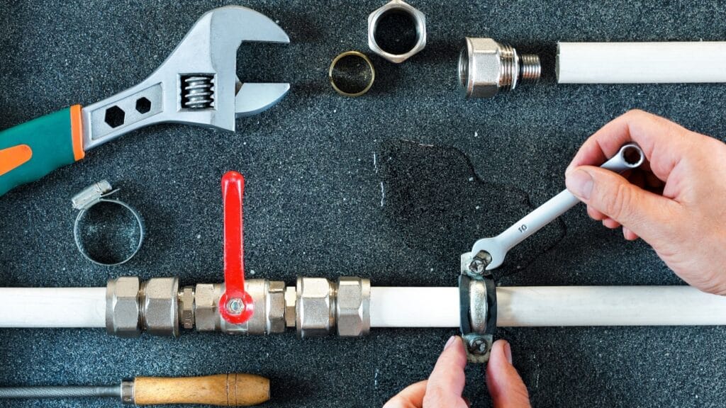 Plumber repairing a pipe valve with an adjustable wrench in Ormond Beach