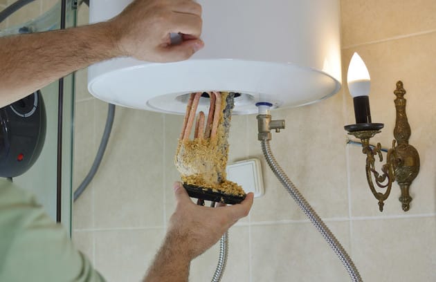 Technician removing mineral buildup from a water heater in Ormond Beach