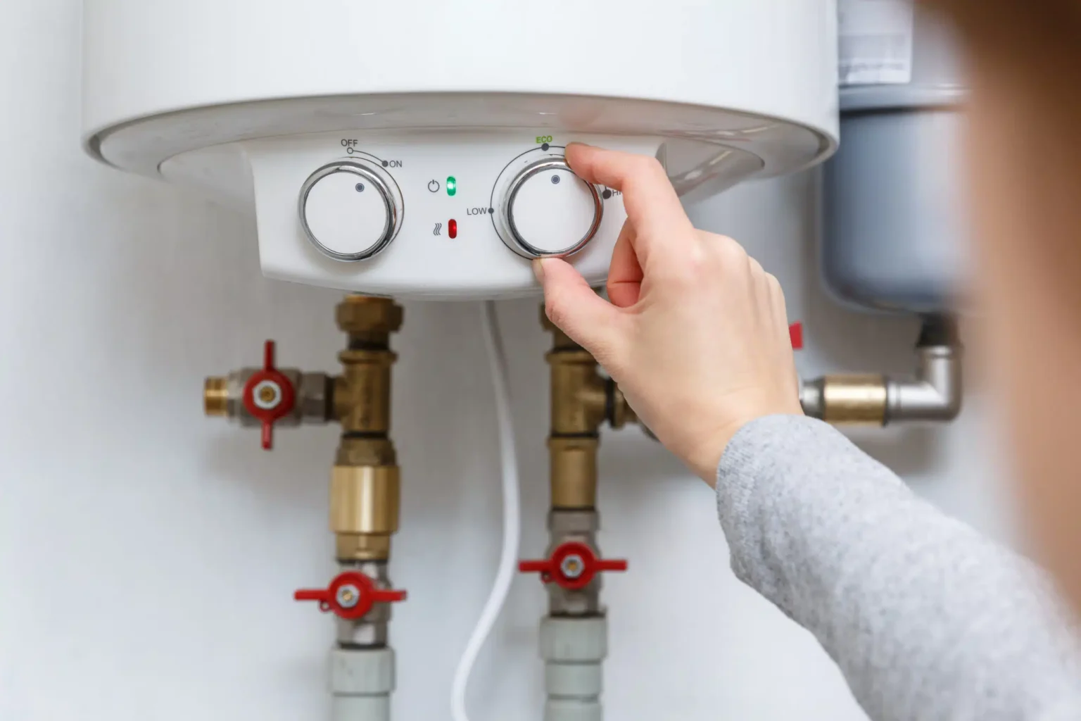 Homeowner adjusting the temperature controls on a water heater in Ormond Beach